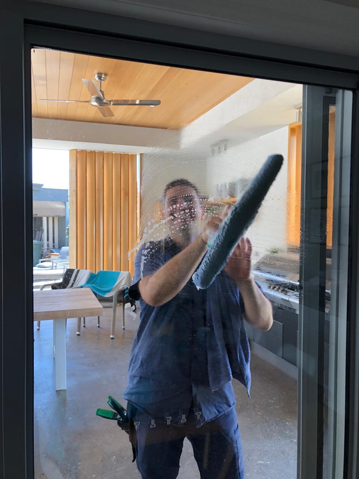 Cleaning the inside of a glass sliding door with a squeegee